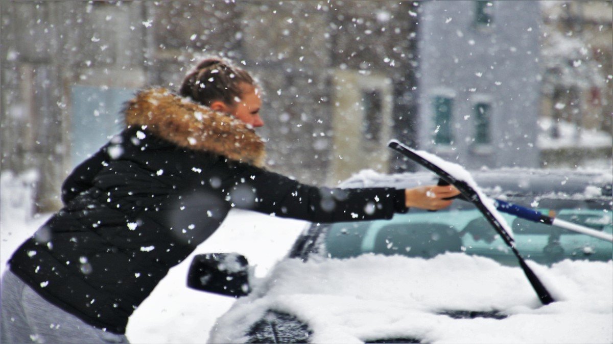 Person clearing snow from car